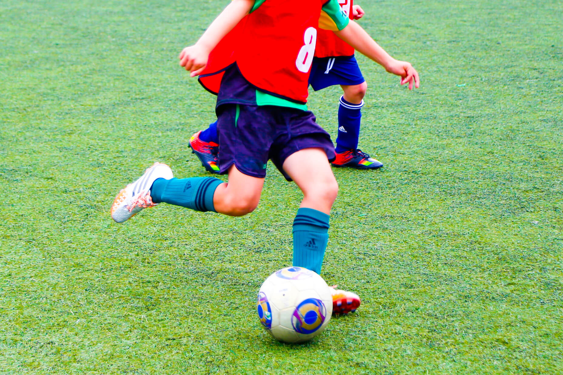 ユニフォームを着たサッカー選手が試合をしている様子